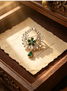 Close-up detail of the vintage emerald wreath brooch with crystal rhinestones and teardrop pendant.
