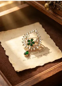 Vintage court style emerald wreath brooch with crystal leaf and teardrop pendant accessory.