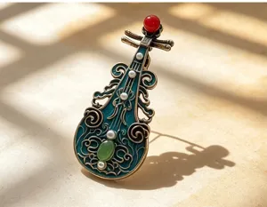Close-up of vintage Chinese Pipa brooch, antique metal with imitation blue enamel and pearls.