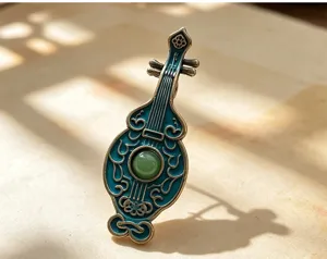 Close-up of retro Chinese pipa brooch, exquisite blue enamel detail and green bead.