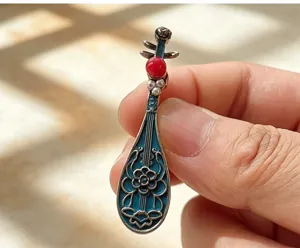Close-up detail of Dunhuang style Pipa brooch with blue enamel and red bead decoration.
