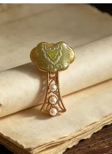 Nahaufnahme eines chinesisch inspirierten Broschen-Details mit zarten Perlen und Metallfiligran.