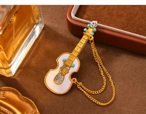 Broche de borla de violín vintage con pedrería brillante y un elegante diseño dorado.