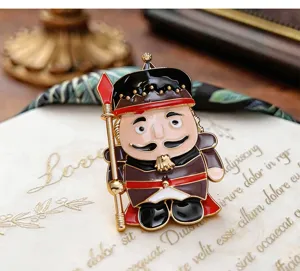 Close-up detail view of the cute nutcracker soldier enamel brooch, featuring metallic gold trim.