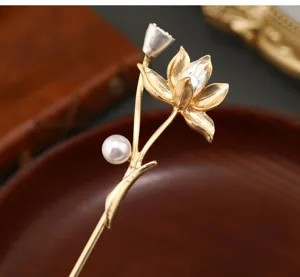 Feines antikes Lotus Haarnadel Detail mit eleganter Perle und goldener Oberflaeche.