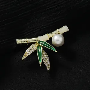 Elegante Bambus-Brosche mit Perle, glänzenden Strasssteinen und grünen Emaille-Details.
