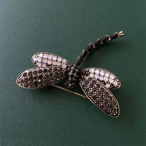 Detailed close-up of a vintage dragonfly brooch sparkling with black and white rhinestones.