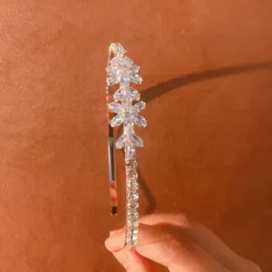 Detail view of a sparkling rhinestone hairband featuring crystal flower clusters on a thin metal band.