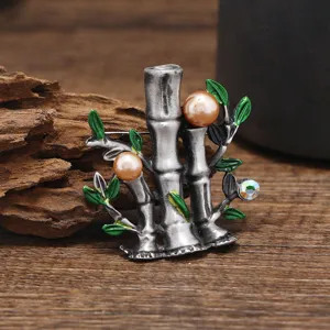 Detailed view of a vintage bamboo pearl brooch with green enamel leaves, elegant jewelry piece.