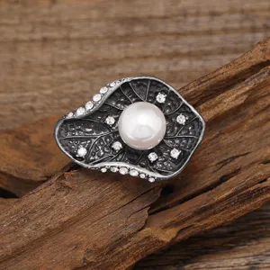 Detailed shot of retro Chinese style lotus leaf pearl brooch with sparkling crystals and metal.