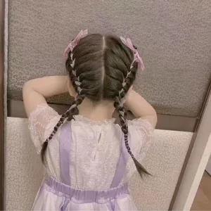 Rückansicht eines Mädchens mit geflochtenen Haaren und lila Schleifen-Haarspangen