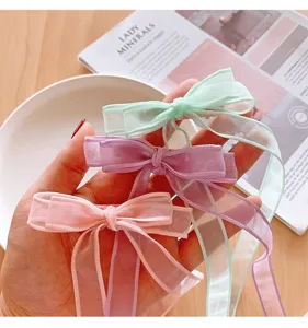 Detailaufnahme von drei pastellfarbenen Organza-Haarschleifen mit langen Bändern.