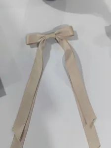 Primo piano di un'elegante fermaglio per capelli con doppio fiocco in nastro champagne.