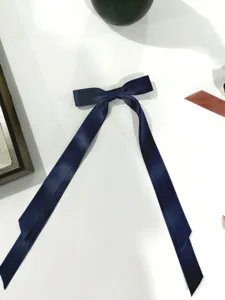 Vista dettagliata del fiocco in raso blu navy con lunghi nastri per i capelli