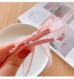 Detailaufnahme einer rosa Schleifen-Haarspange mit stoffbezogener Krokodilklemme.
