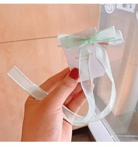 Detailansicht einer hellgrünen Organza-Schleifen-Haarspange mit Bändern.