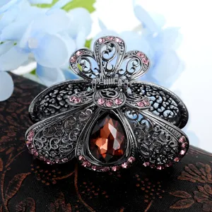 Primo piano di artiglio per capelli in metallo con strass rosa e grande pietra marrone centrale.