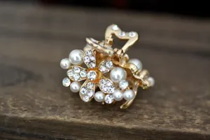 Gold tone mini hair claw clip featuring sparkling rhinestones and elegant pearls in flower shape.
