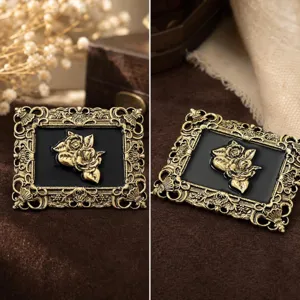 Detailed view of vintage baroque metal brooch with black enamel and gold rose relief design.