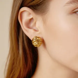 Close-up detail of vintage textured gold metal stud earrings worn on ear, elegant design.