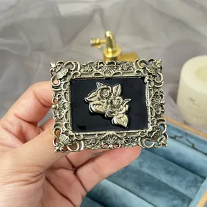 Detailed shot of vintage gold metal brooch with black enamel and 3D rose relief design.