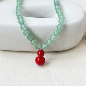 Close-up view of the green aventurine bead necklace with red gourd pendant detail.