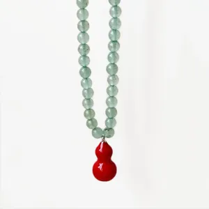 Green aventurine bead necklace detail with vibrant red gourd pendant, elegant close-up view.