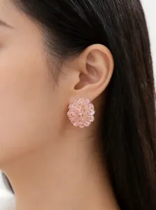 Nahaufnahme Detail eines rosafarbenen Kristall Blumen Ohrsteckers am Ohr getragen, eleganter Stil.