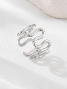 Close-up detail of the minimalist silver wavy open ring, sleek stainless steel texture.