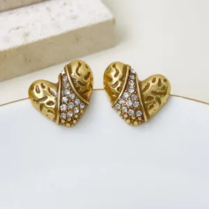 Nahaufnahme von goldenen Vintage-Strass-Herz-Ohrringen mit Hohlmuster und Kristallen.