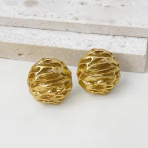 Close-up shot of vintage textured gold metallic earrings, showing organic irregular surface detail.