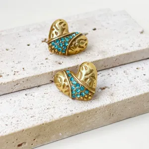 Nahaufnahme von vintage goldenen Herz Ohrringen mit funkelnden blauen Kristall Strasssteinen.