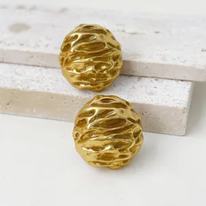Vintage textured metal earrings detail shot, minimalist high-end gold statement jewelry.