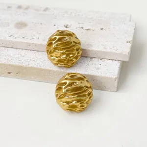Textured metal earrings detail shot, vintage gold designer style jewelry, elegant fashion accessory.