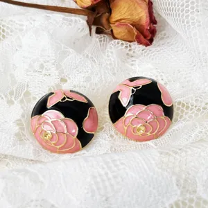 Detailaufnahme von retro rosa schwarzen Emaille Blumen Ohrringen mit goldenem Rand.