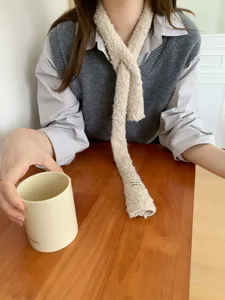 Primo piano di una sciarpa a maglia stretta e accogliente, design incrociato beige.