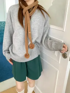 Nahaufnahme Detail eines koreanischen Stils gestrickten schmalen Schals mit Bommel im Innenbereich.
