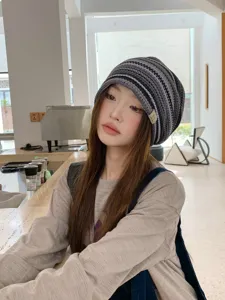 Detail view of a vintage striped knitted slouchy beanie hat worn by a model, casual style.
