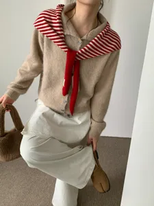 Detailed shot of knitted cardigan with striped scarf shawl and layered skirt for winter outfit.
