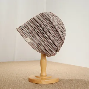 Detailed view of retro striped knitted slouchy beanie hat texture and woven brand label design.
