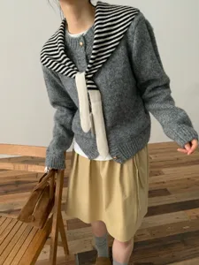 Stylish winter women knit cardigan with striped scarf and skirt set, cozy chic detail view.