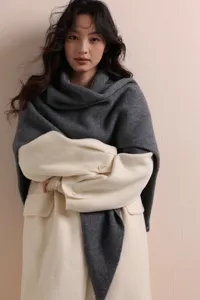 Strickschals Detailansicht, gemütlicher grauer Winterschal über weißem Mantel, weich.