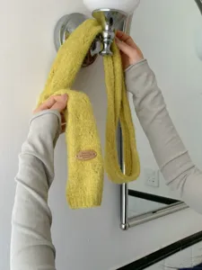 Senfgelber Strickwollschal mit dekorativem Leder-Logopatch für Damen im Winter.