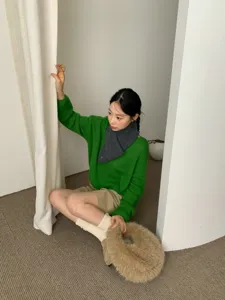 Detailaufnahme des grauen Woll-Spitzschals, getragen vom Model mit grünem Pullover, wärmend.