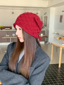 Nahaufnahme Detail der roten gestrickten Beanie Mütze mit Fischgrätenmuster und Glitzerfäden.
