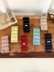 Gros plan détaillé de mini écharpes en tricot coloré disposées proprement sur une table en bois.