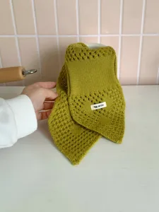 Nahaufnahme des olivgrünen Strick-Halswärmers mit Lochmuster, gemütliches Winterdesign.
