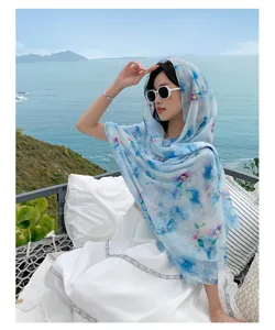 Nahaufnahme einer blauen Blumendruck Strandschal als ein sehr stilvolles Kopftuch am Meer.