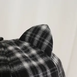 Primer plano detallado de un gorro a cuadros blancos y negros con orejas de gato.