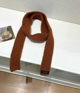 Detailed close-up of a stylish brown knit baguette scarf, minimalist solid color winter accessory.